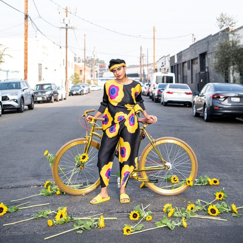 Portrait of Madame Gandhi with a bike and sunflowers around the Arts District.